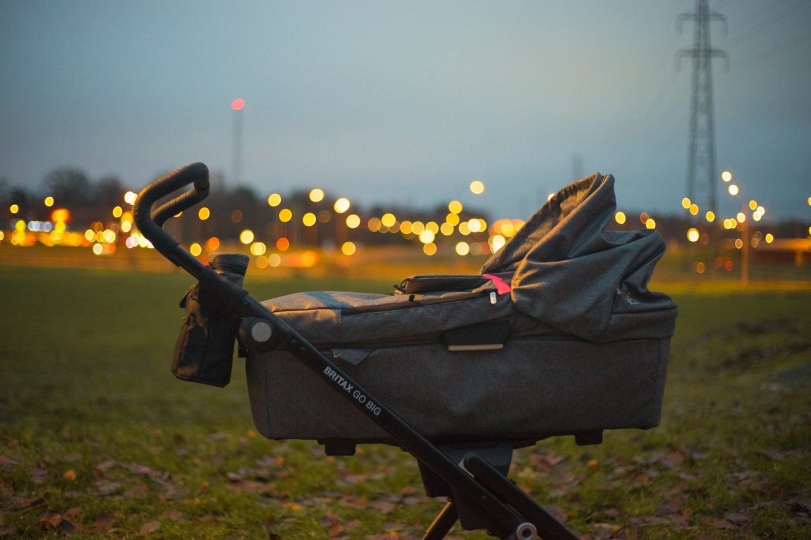 selective focus of gray bassinet stroller on green grass
